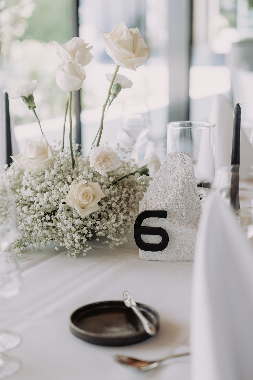 Centre de table en roses blanches, mariage blanc et noir décoré par Mona Ilsa, décoratrice de mariage