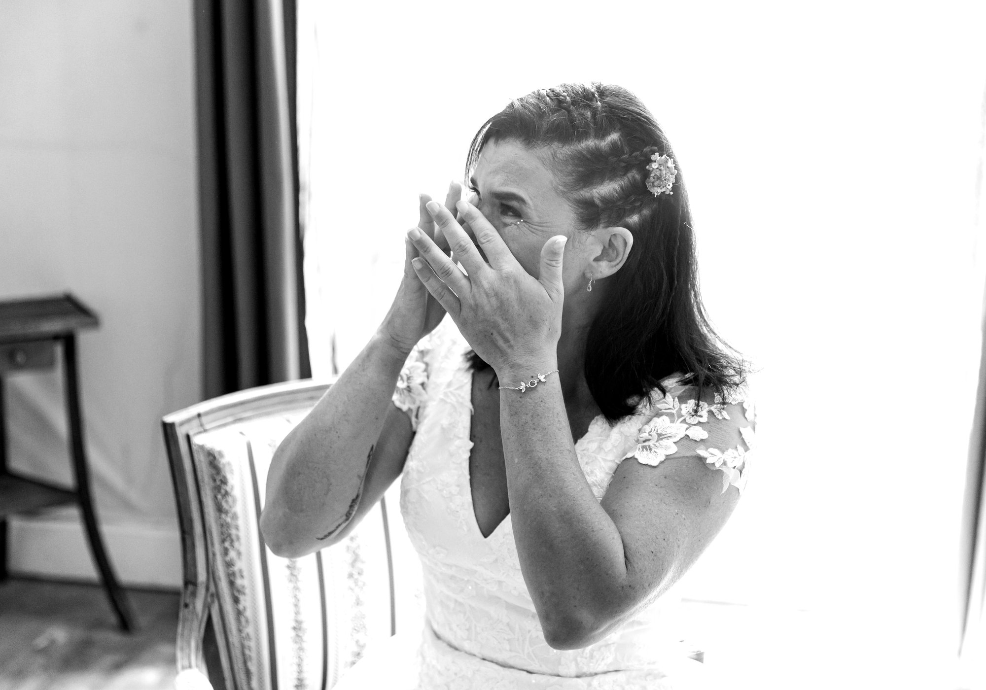 La mariée essuie une larme d'émotion, en noir et blanc