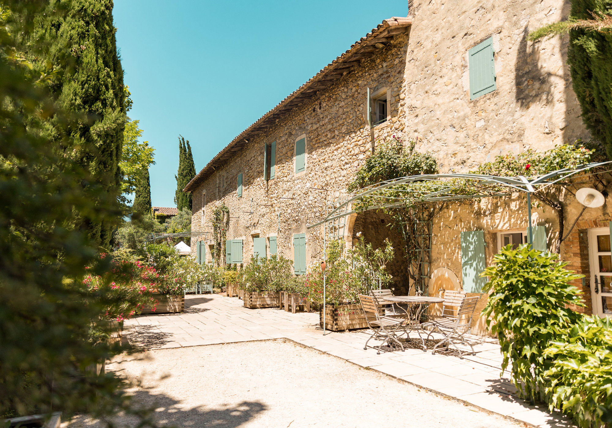 La bâtisse en pierre du domaine, volets pastel et lauriers en fleurs