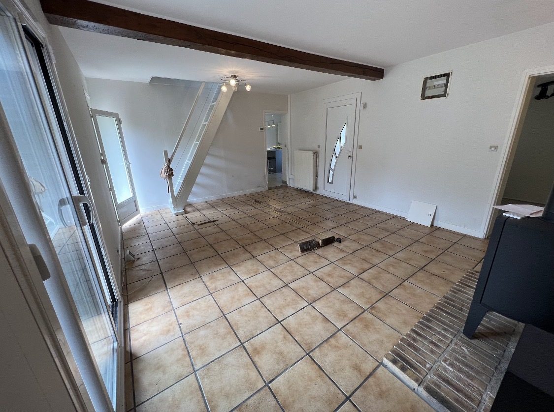 Le salon vide avant les travaux, sol carrelé et murs blancs