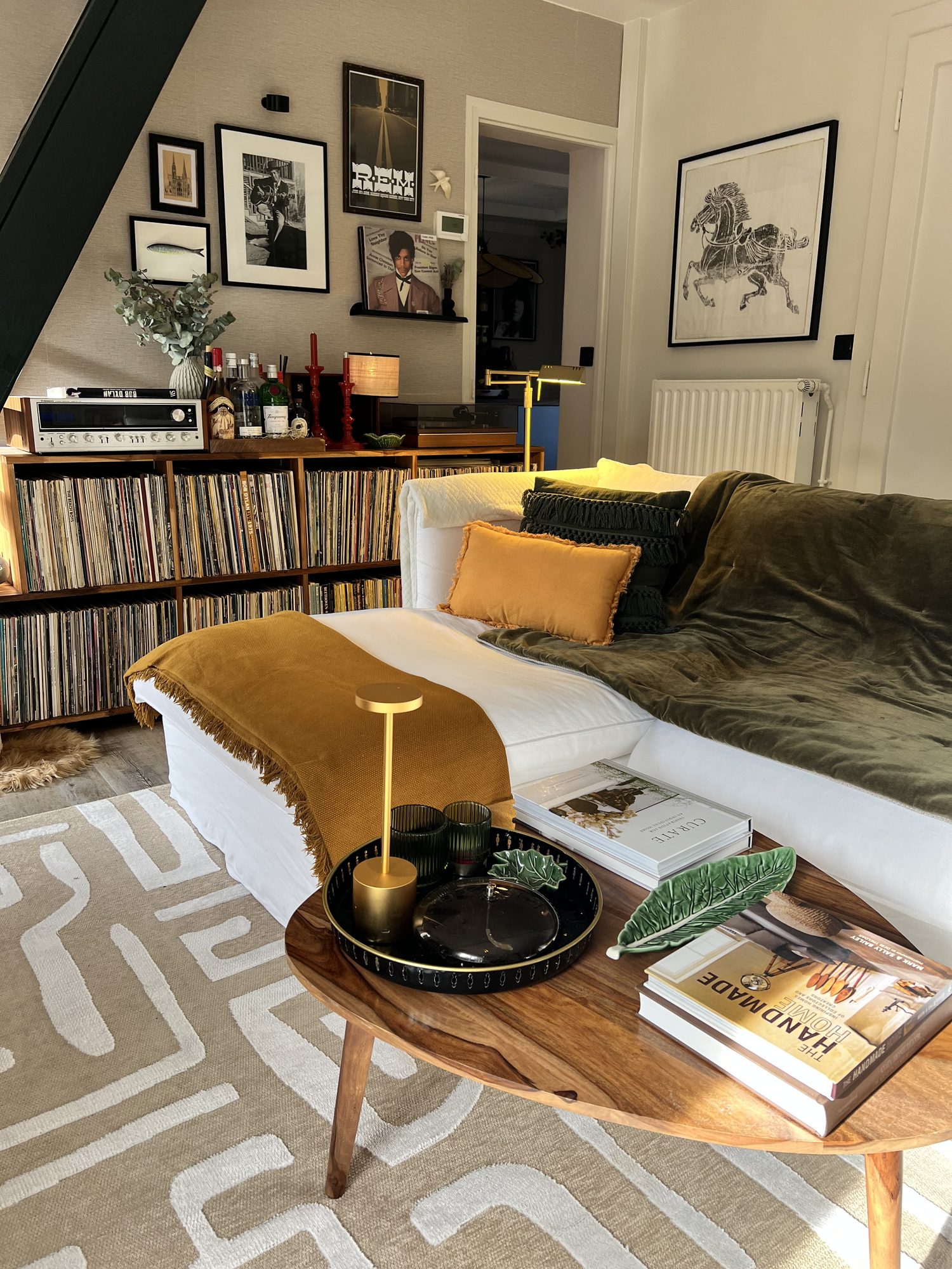 Coin salon avec collection de vinyles, mur de cadres et velours vert