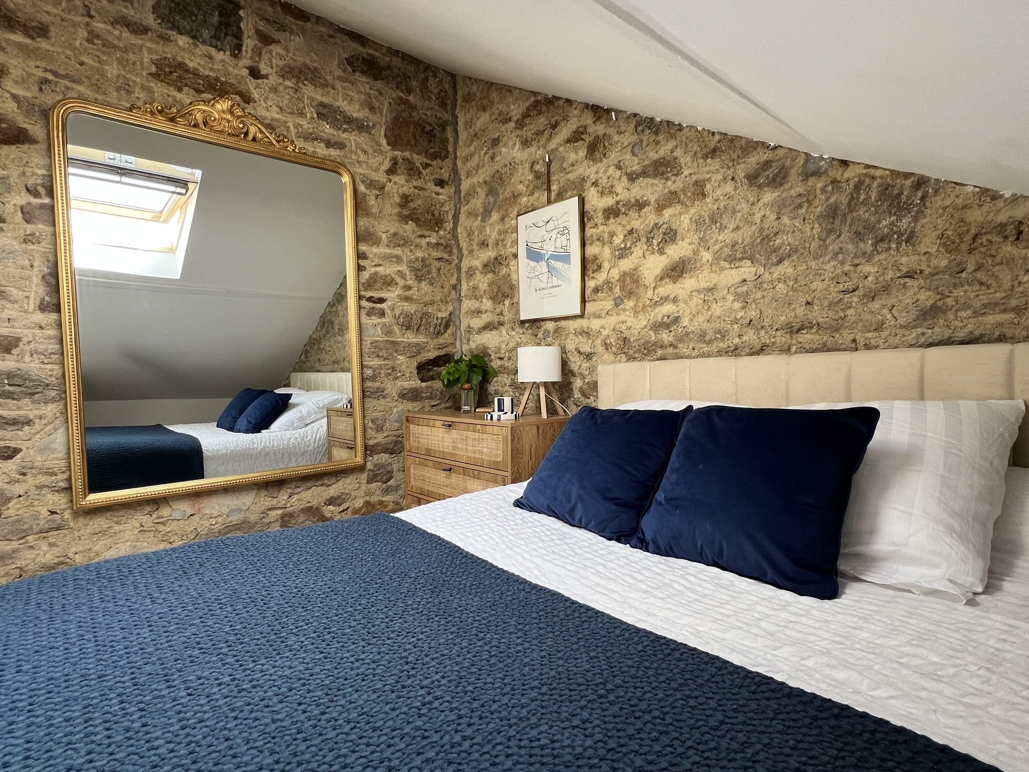 Chambre sous les combles, mur en pierre et linge de lit bleu marine