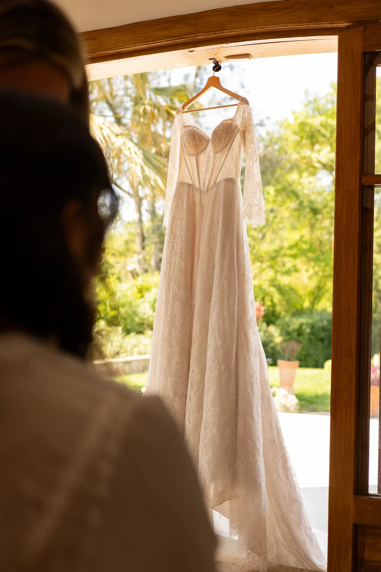 La robe de mariée suspendue près de la fenêtre, jardin en arrière-plan