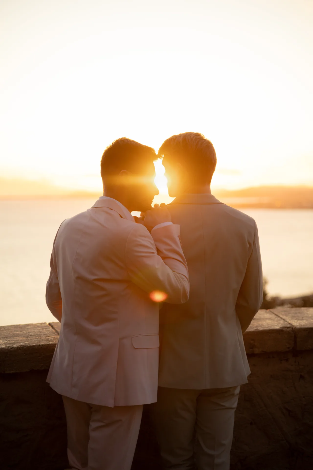 Un couple s'embrassant en silhouette au coucher du soleil, face à la mer